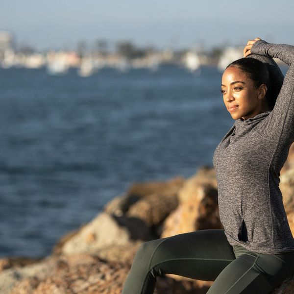Silhouette of a woman stretching against a sunrise background.